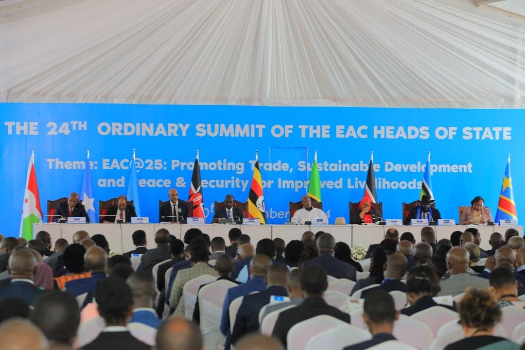 East African heads of state seated on a platform beneath a banner reading The 24th Ordinary Summit of the EAC Heads of State, delegates filling the hall in front of them.
