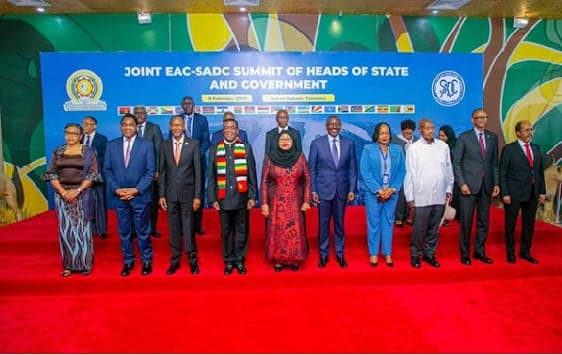Heads of state and government standing in a line on a red carpet for a group photograph in front of a Joint EAC-SADC Summit backdrop.