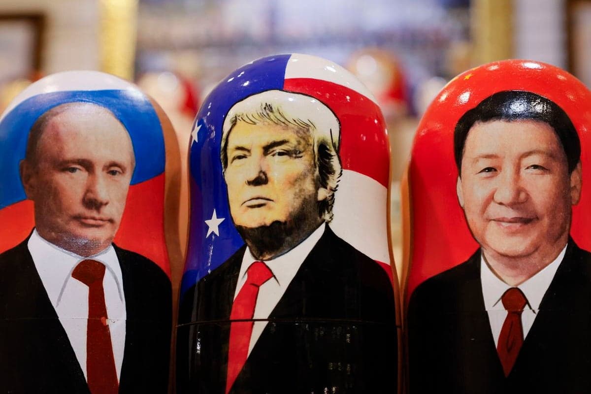 Three matryoshka dolls painted with the faces of Vladimir Putin, Donald Trump and Xi Jinping, each in their country’s flag colours.